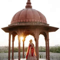 A stunning bridal portrait of Muskan, framed perfectly within a royal gazebo at sunset, blending architectural beauty with golden hour light.