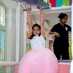 Building strength and having a blast! A young guest enjoys the monkey bars and zipline in our padded soft play area, with our attentive staff nearby.