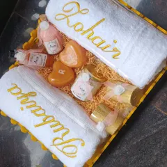 My signature golden-themed wedding hamper is a bestseller for a reason. It includes white towels with beautiful gold name embroidery, heart-shaped initial soaps, luxury candles, and a curated selection of my spa products.