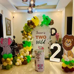 We transformed this living room into a "Two Wild" jungle safari for a second birthday party. This setup includes a personalized backdrop, a full balloon arch in jungle colors, cute animal cutouts of a lion and elephant, and a light-up number '2'.
