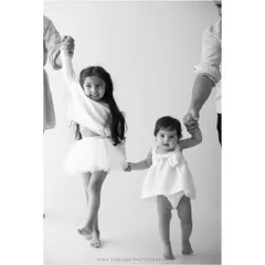 The beginning of a lifelong friendship. This sibling photography moment captures the sweet bond between sisters as they walk hand in hand, guided by their parents.