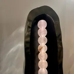 A sculptural floor lamp by Nituṣhā, featuring a stack of illuminated stone spheres within a dark metal shroud. This piece is a powerful example of how light and material can be combined to create a dramatic, artistic statement.