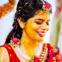 A candid shot of the bride's joyful reaction during her Haldi ceremony, covered in turmeric and flowers.