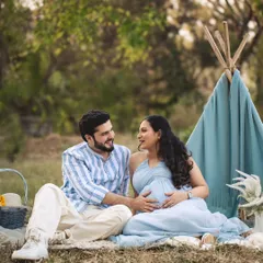 A sweet moment during their outdoor picnic session. The simple teepee and natural setting create a relaxed, bohemian vibe for this romantic couple's portrait.