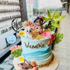 A detailed and beautiful Moana themed cake, identical to my featured design. It showcases hand-sculpted fondant figures of Moana and Pua on a sandy beach setting with buttercream waves.