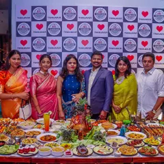 Happy guests gather around our lavish buffet table during a launch event. This showcases how our extensive food spread becomes a central point of celebration and enjoyment at any gathering.