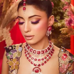 A closer look at the details of this artistic look, with the pop of purple on the eyes complementing the ruby jewelry and floral embroidery.