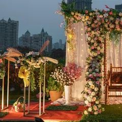 This angle showcases the depth of the outdoor setup, with the floral arrangements in the foreground and the decorated swing against the city lights in the background. It highlights the layers of detail in the decor.