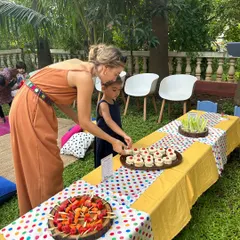 A mother and daughter picking out treats from the colorful food table. I design my kids' party spreads to be visually exciting, with items like fruit skewers and mini sandwiches.