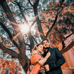 A sun-kissed embrace under a sprawling tree, with the heritage architecture in the background. This shot perfectly blends nature with royal history.