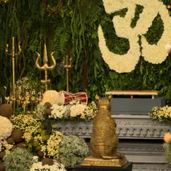 The heart of the celebration. The main altar features a floral 'Om' symbol, a golden Mooshak statue, and an abundance of fresh flowers against a living wall of greenery.