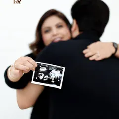 A first glimpse of their little one. This artistic shot focuses on the ultrasound scan held by the mother, with her and her partner embracing in the background, beautifully capturing the emotion of the moment.