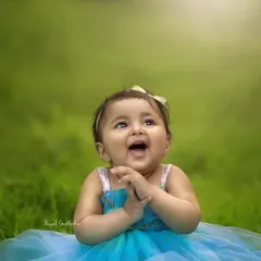 The pure, uncontainable joy of a toddler. Her happy expression and bright blue dress against the vibrant green grass show that the best photos come from letting kids just be themselves.