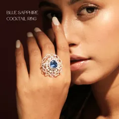 A moment of midnight magic. This Blue Sapphire Cocktail Ring, featuring a vibrant central sapphire crowned with pear and round shaped diamonds, is shown on a model to highlight its captivating presence.