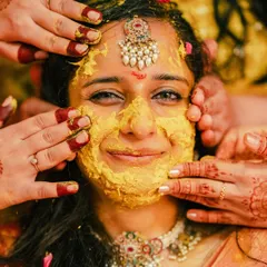 A close-up of the bride's face covered in turmeric paste, her smile shining through. This shot captures the playful and intimate nature of the Haldi ceremony.