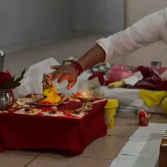 A hand makes an offering to a small deity during a puja ceremony. These rituals, while rooted in tradition, are a part of the vast science of spirituality that helps focus the mind and heart.