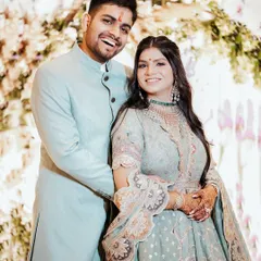 A joyful, candid portrait of a couple at their Roka ceremony, laughing together in front of a beautiful floral arch.