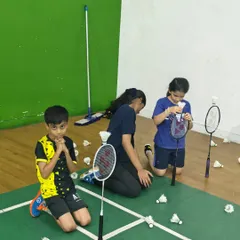 A moment of fun and teamwork as kids gather shuttles after a drill. I believe in teaching discipline and responsibility on the court in an engaging way.