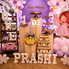 A display of luxurious props for a butterfly-themed party, including gold dessert stands, marquee letters, and a light-up crown.
