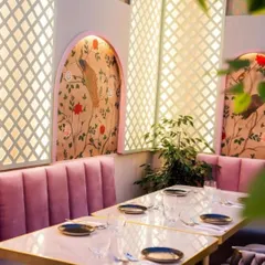 This restaurant's dining nook is elevated with an elegant, custom-fit peacock mural inside an arched alcove. The soft colors and intricate design work with the pink upholstery to create a chic and photogenic dining spot.