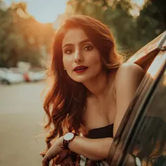 A classic golden hour portrait taken from a car window. The warm light illuminates the subject's face, creating a soft and cinematic shot that feels like a still from a movie.