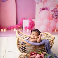 A butterfly-themed session with a beautiful purple and pink colour palette. This little one is sleeping so peacefully in her wicker pram.