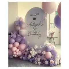 An elegant welcome sign for 'Aaliyah's 1st Birthday'. The frosted acrylic sign is surrounded by a beautiful arrangement of pink and lavender balloons and flowers, setting the tone for a royal celebration.