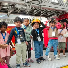 A group of children stands proudly on a fire truck during our visit to the local fire station. Meeting community helpers in person makes their roles real and memorable.