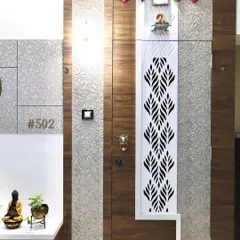 The safety door for this entrance features an intricate white jali panel set against a wood-finish door. The design combines traditional motifs with modern materials for a unique look.