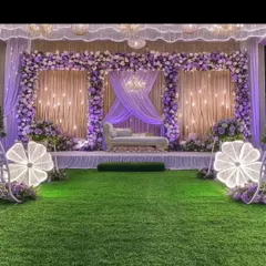 For a grand Sangeet or reception, I can design an elegant stage like this one. It uses a beautiful lavender and white floral theme, soft drapery, and unique lighted floral props to create a magical atmosphere for your celebration.