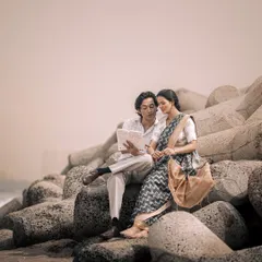 A quiet moment reading the paper together by the sea. This image is styled to feel like a memory from another time, focusing on the connection and shared peace between the couple.