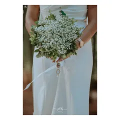 The bride's bouquet of baby's breath is simple, elegant, and timeless, perfectly complementing her modern wedding dress.