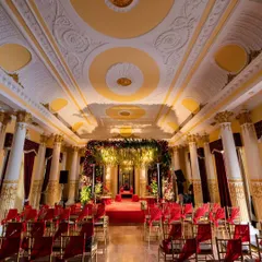 The grand Durbar Hall at Lalitha Mahal Palace set up for a royal wedding ceremony, with red and gold decor complementing the room's opulence.