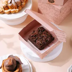 This shot showcases the brownie in its beautiful packaging, telling a story of a premium, gift-worthy product. It's a great example of lifestyle product photography for a dessert brand.