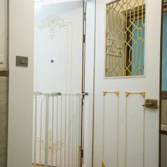 A classic and elegant entrance. The white safety door features a gold geometric grill and decorative corner details, creating a look inspired by Regency-era design.
