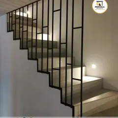 This interior staircase features a modern, minimalist railing with a geometric pattern. The clean lines and black finish create a contemporary look that adds a graphic element to the space while ensuring safety.