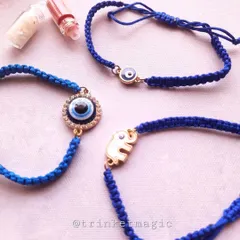 Simple, elegant, and protective. This collection of evil eye Rakhis features an elephant charm for good luck and a classic round evil eye charm, all on a traditional blue thread.