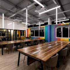 This open-plan workspace features a custom installation of suspended LED tubes. The arrangement is designed to provide excellent, uniform light for working while creating a sense of energy and movement that reflects a modern, dynamic company culture.