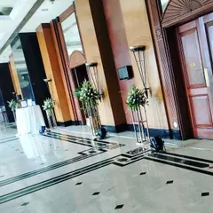 Simple yet effective decor for a hotel corridor. We used tall, minimalist stands with fresh white flower arrangements to line the walkway, adding a touch of class to the space without feeling cluttered.
