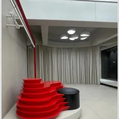 A key feature of the ARKS store is the vibrant red, multi-level display unit. Its organic, flowing shape provides a dynamic platform for showcasing products like shoes and accessories, adding a burst of energy to the minimalist space.