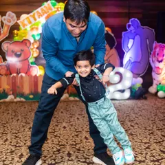 A father playfully swings his son at his second birthday party, a moment of pure fun and connection.