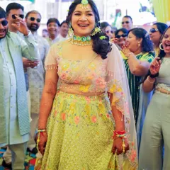 The bride's grand entrance at her Haldi. Her makeup is kept light and dewy, allowing her natural happiness to shine through as she's surrounded by loved ones.