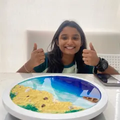 The finished product. A student gives a thumbs up, thrilled with the resin beach art she created. Our workshops are designed to ensure everyone leaves with a piece they are proud of.