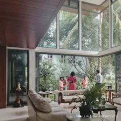A double-height glass wall in this living room frames the garden like a living painting. This not only floods the space with light but also makes the lush greenery an integral part of the interior decor.