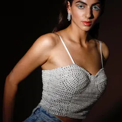 A striking portrait featuring a hand-beaded bustier. The dramatic lighting and bold white eyeliner create a futuristic, high-fashion look that is both strong and delicate.