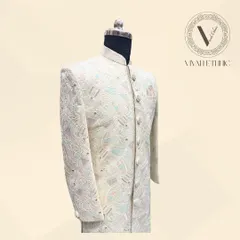 A closer look at the elegant ivory sherwani. Notice the fine threadwork and the subtle blend of pastel colors, designed for a sophisticated groom.