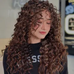 These curls are making their own rules. This shot shows the incredible volume and texture we achieved with a specialized curly cut and style.