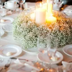 An elegant table centerpiece featuring a wreath of baby's breath flowers surrounding pillar candles. This simple yet beautiful detail adds a touch of class to any corporate dinner table.