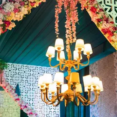 This shot highlights the combination of lighting and floral decor. A classic chandelier hangs at the center of a grand archway, which is adorned with pink and white flowers and intricate latticework.