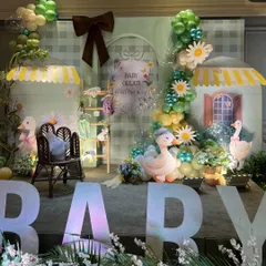 A wide view of the stage setup, with large light-up "BABY" letters and a charming scene featuring duck props and market stall awnings.